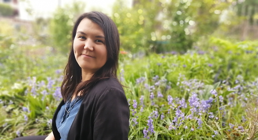 Inuk editor Rachel Taylor is shown from the waist up. She is smiling in a garden, wearing a black blazer and blue top. 